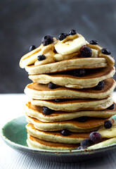Stack of American pancakes with peanut butter, banana and blueberries.