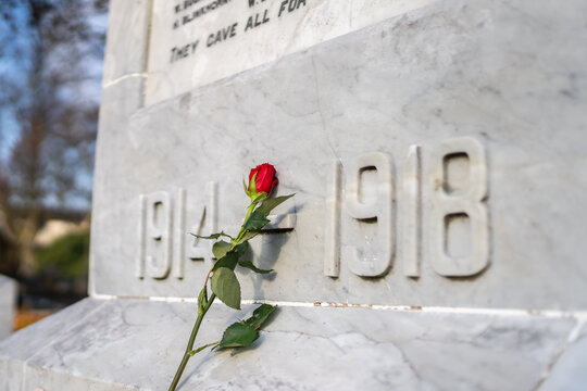Single red rose placed against marble Great War soldier memorial on Sunday 11th November remembrance day for those who lost their lives 1914 1918