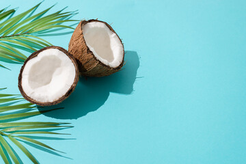 Summer flat lay scene with palm leaf and coconut fruits on blue background. Top view, copy space....