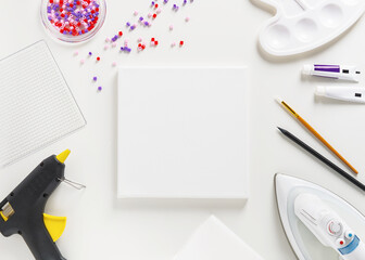 The workplace of the artist with collection of crafts equipment: canvas, iron beads, brush, pen,...