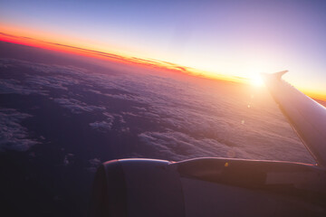 Top view from inside window airplane of a sunset sky and wing