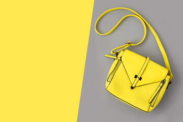 Fashion woman yellow bag on gray background. Trendy Color of Year 2021. Illuminating Yellow and Ultimate Gray. Flat lay, top view. Copy space. Fashionable leather bag