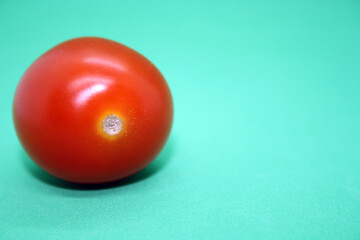 Small cherry tomatoes isolated on a green background.