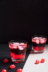 Copa de cóctel rojo con cerezas rojas sobre fondo negro y gris