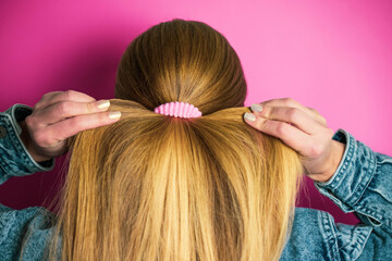 Fototapeta premium Girl doing her hair with a pink hair tie
