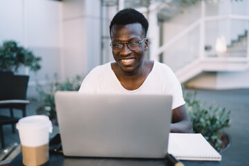 Happy young man using laptop in park cafe