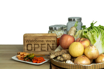An open sign on table with fruits and vegetables and kimchi. Open sign near organic food ingredients on wooden table. Vintage wooden open sign on table with fresh vegetables basket.
