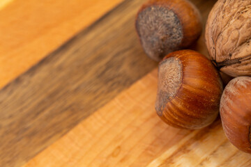 A mixture of hazelnuts and walnuts on a cutting board. Soft, artificial light, copy space available