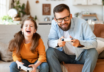 father and daughter laugh and play video games together using a video game console © JenkoAtaman