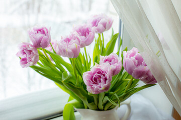 a vase of tulips stands on the window
