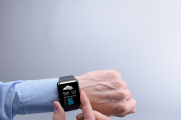 Close-up of a businessman man male checking weather on smartwatch app program on a background of blue sky with white clouds