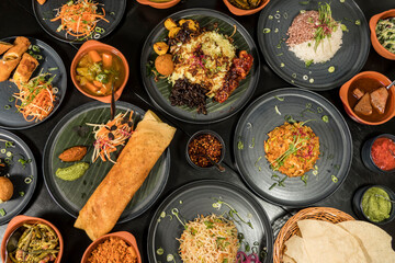 An assortment of Sri Lankan dishes and papadam bread and a chicken dosa in the middle.