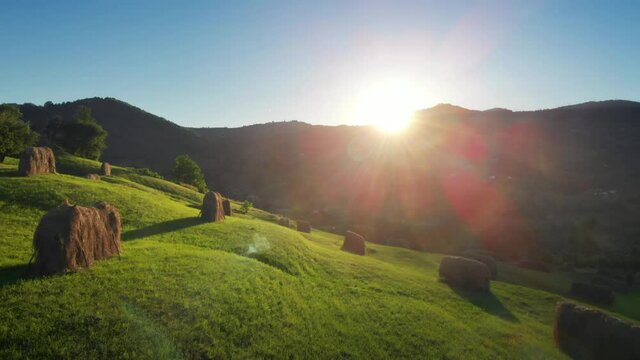 Peaceful nature scene, flying over the hills aerial footage, green farmland with haystacks in Romania