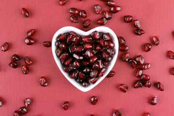 Pomegranate fruits on a red background. Pomegranate background. Heart shaped plate