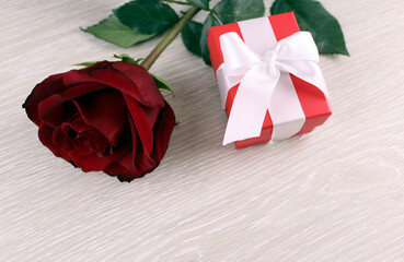 Red rose with red gift box on wooden background