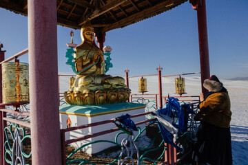 Woman is standing in front of statue of Buddha. Buryatia region of Russia.