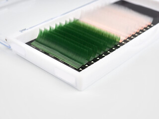 Multi-colored artificial eyelashes for extension, two colors in the macro palette, green and white.