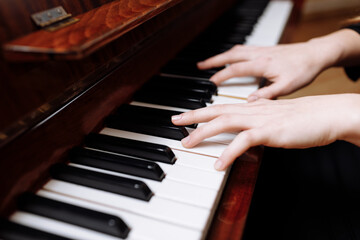 Close up of the hands of a young woman playing piano