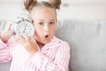 Little girl and alarm clock. Funny child with clock in the morning.