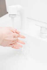 Woman washing hands in the washbasin (bathroom sink)