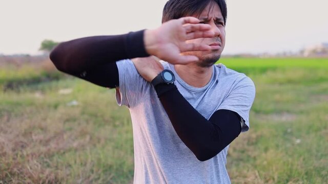 Young asian man with shoulder pain from exercising in the park