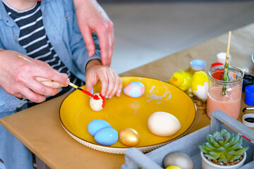 Obraz na płótnie Canvas Little boy painting wooden eggs for Easter decoration