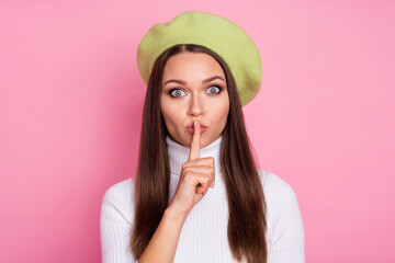 Portrait of lovely straight-haired girl showing shh symbol don't speak isolated over pink pastel color background