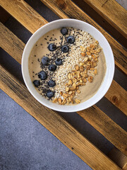 smoothiebowl with chia seeds, blueberry and granola on a wooden box