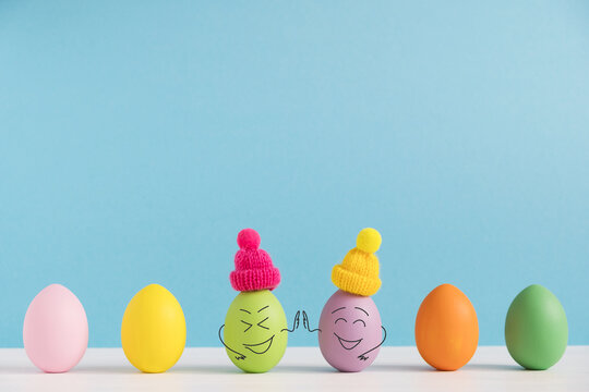 Friends high five to each other. Positive eggs in hats. Easter holiday concept with cute eggs with funny faces. Different emotions and feelings.