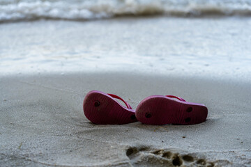 Red slippers on the beach. Thongs on the beach