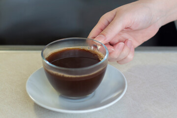 Women's hands hold a cup of coffee over the table. Breakfast with coffee. Make coffee in a turk.
