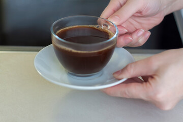 Women's hands hold a cup of coffee over the table. Breakfast with coffee. Make coffee in a turk.