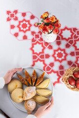 Beautiful Novruz table set up with national pastry in white plate with dyed red eggs and flowers in red and white colors. Celebration of spring equinox in Azerbaijan in March. Flat lay  copy space