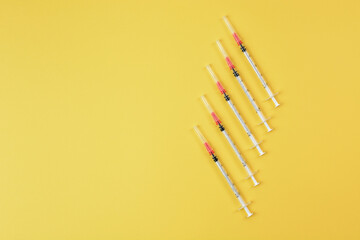 Group of syringes on yellow background. Coronavirus vaccine and injections concept. Flu vaccination.