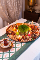 Novruz traditional tray with green wheat grass semeni or sabzi, sweets and dry fruits and festive candles with tea. Traditional celebration of spring equinox in March in Azerbaijan 