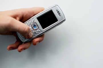 Old 2000s phone in hand. Nostalgia retro phone. 