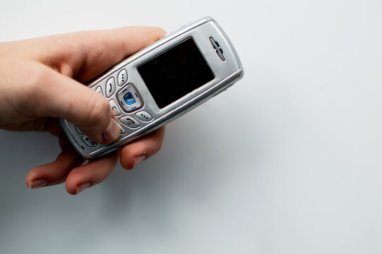 Old 2000s phone in hand. Nostalgia retro phone. 