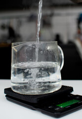 Bubbles in hot water boiling inside glass transparent teapot. Close up of boiling water in transparent kettle on kitchen scales. Splashing water bubble background.