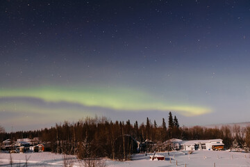 Northern Lights in the starry sky above the village. Night landscape