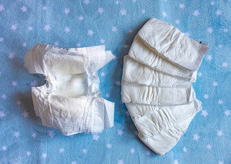 White disposable diapers for little babies on blue background with stars. Top view, selective focus