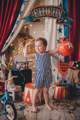 A white boy lifts a circus weight. Stylized circus photo zone.