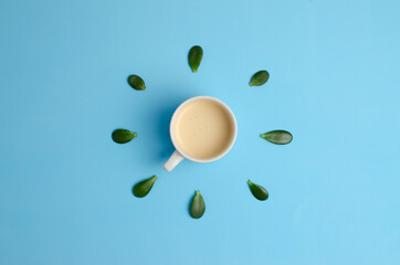 morning cup of coffee on a blue background with leaves around it