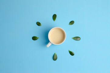 morning cup of coffee on a blue background with leaves around it