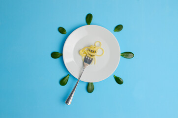 a fork with pasta lying on a white plate blue background