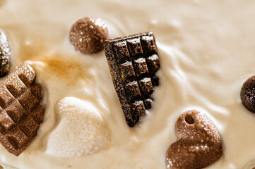 chocolate hearts and bars drowning in milk chocolate, close up