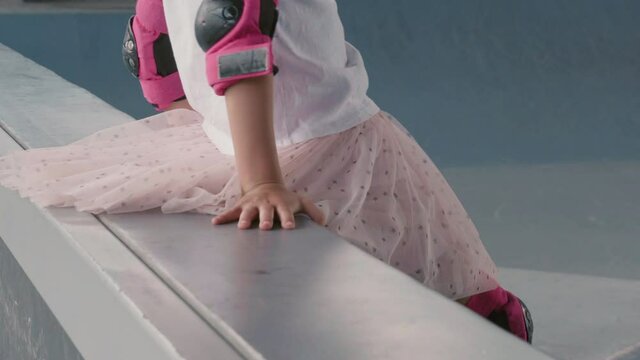 Real time of two little Caucasian girl wearing safety helmets, elbow and knee daps skating in indoor skating arena