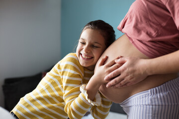 Daughter touching the belly of her pregnant mother.