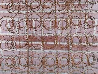 rusty spiral from an old mattress leaning against a brick wall