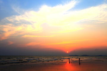 Silhouette two people walking along the beach when the sun sets.