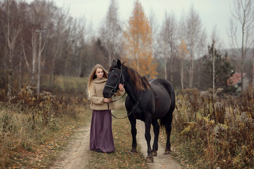 beautiful girl stands with hors  in autumn 